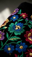 Colorful floral embroidery on black fabric with vibrant thread work featuring traditional folk art patterns for textile and fashion design projects.