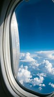 Aerial view through airplane window showing white fluffy clouds against clear blue sky, perfect for travel, aviation, and journey-themed designs.