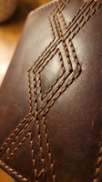 Close-up of brown leather with decorative stitching pattern showing craftsmanship and texture detail for luxury goods and fashion accessories design.