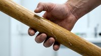 Senior man's weathered hand gripping wooden handrail for support and stability while walking, showcasing aging, mobility assistance, and safety measures.