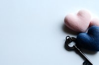 Vintage black key with pink and navy blue felt hearts on white background, romantic concept for Valentine's day cards and love messages.