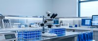Modern laboratory interior with microscope and blue test tube racks on white countertop. Clean scientific workspace for research and analysis.