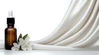 Amber glass dropper bottle with white jasmine flower against flowing white silk fabric background, minimalist spa and wellness composition.