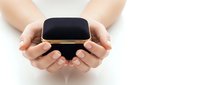 Hands gently holding modern black smartwatch with golden accents in cupped palms against clean white background for technology and wearable device concepts.