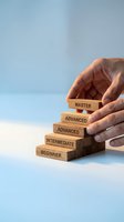 Hand protecting wooden blocks showing skill levels from beginner to master representing career development and professional growth progression.