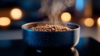 Fresh roasted coffee beans steaming in dark blue ceramic bowl against blurred warm bokeh lights background, moody atmospheric food photography composition.