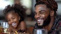 Young African American couple enjoying romantic dinner with wine and food at restaurant, sharing genuine laughter and intimate moment during date night.