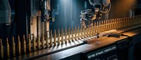 Industrial ammunition manufacturing line with brass bullets in precision assembly process for military and defense production applications.