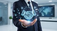 Professional businessman in suit holding holographic handshake icon with global network connections in modern office environment for partnership concepts.
