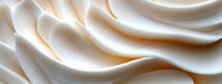 Smooth waves of white cream forming soft peaks and swirls in macro photography, creating abstract curves and lines against light background. Suitable for food industry.