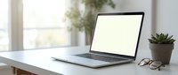 Laptop with blank screen on white desk next to potted succulent plant and eyeglasses, bright window background, workspace setup for web design and business presentations.