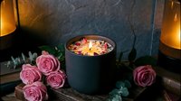 Acai bowl with granola and berries surrounded by pink roses and candles creating romantic breakfast atmosphere on dark wooden surface.