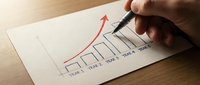 Hand drawing upward trending business graph with red arrow on paper, showing growth strategy and financial success planning for presentations and reports.