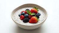 Chia seed pudding topped with fresh mixed berries including strawberries, blueberries, raspberries and blackberries in ceramic bowl for healthy breakfast.