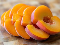 Fresh ripe peach slices arranged in row on wooden surface, showing juicy orange flesh and pink skin, macro food photography with soft lighting.