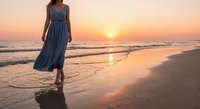 Young woman in flowing blue dress walking barefoot on sandy beach at golden sunset with ocean waves and warm evening light creating peaceful seaside atmosphere.