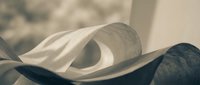 Rolled white and dark fabric sheets with soft folds and curves, creating abstract textures and layers for design, textile, and creative projects.