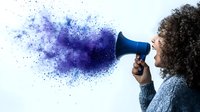 Young African American woman with curly hair holding megaphone with purple and blue powder explosion effect, representing powerful voice and communication on white background.