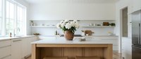 Bright modern kitchen with white walls, open shelving, wooden island, and fresh white flowers in a terracotta vase, clean Scandinavian style.