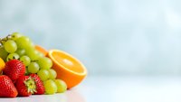 Fresh colorful fruit assortment with strawberries, grapes and orange slices on clean white surface for healthy eating and nutrition concepts.