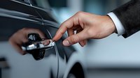 Male hand in business suit sleeve unlocking modern car door with key, close-up view showing luxury vehicle detail and professional appearance.