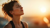 Young woman with closed eyes enjoying sunset, face illuminated by golden hour light, expressing serenity and mindfulness during outdoor meditation practice.