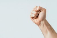 Raised clenched fist of a light-skinned person against white background showing power, protest, unity and strength gesture. Isolated photo for multiple design uses.