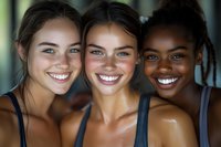 Three diverse young women smiling together in athletic wear showing friendship and teamwork after workout or fitness training session.