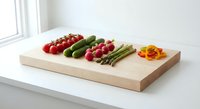 Fresh organic vegetables arranged on wooden cutting board including tomatoes, cucumbers, radishes and asparagus for healthy cooking and meal preparation.