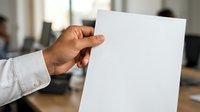 Male professional in white shirt holding blank white paper sheet in modern office environment for business communication and presentation purposes.
