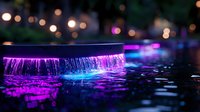 Illuminated waterfall with vibrant purple and blue lights creating magical atmosphere at night, water streams reflecting neon colors against dark background.