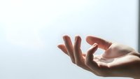 Open cupped hands in gentle receiving gesture against soft light background for meditation, prayer, wellness and spiritual concepts.