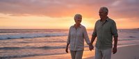 Senior couple walking hand in hand on beach at sunset enjoying romantic evening stroll along ocean waves during golden hour vacation getaway.