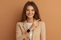 Young Asian businesswoman in beige blazer and white top smiling confidently against brown background, wearing smart watch and showing positive professional attitude.