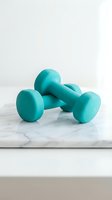 Pair of turquoise dumbbells arranged on white marble surface, isolated on light background. Suitable for fitness, wellness, gym training, and health-related design projects.