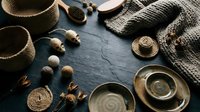 Rustic handmade pottery bowls and woven baskets with natural textures on dark slate surface. Artisan crafted ceramics and fiber art for home decor styling.