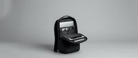 Modern black laptop backpack open displaying organized compartments for tech gear and accessories on neutral background for business travel.