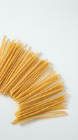 Uncooked spaghetti pasta arranged in bundles on white background, isolated and ready for food, cooking, and culinary design projects.