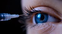 Medical procedure close-up showing syringe near bright blue eye with long eyelashes, demonstrating ophthalmological treatment or eye surgery concept.