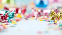 Colorful party celebration background with confetti, streamers and festive decorations scattered on white surface for birthday events and holidays.