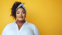 Young African American woman with curly hair and headband wearing white shirt against bright yellow background for lifestyle and fashion content.