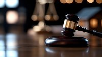 Wooden judge gavel on dark wooden table against blurred background with bokeh lights, dramatic lighting emphasizes legal and justice concept.