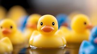 Yellow rubber duck toy in focus with blurred ducks in background creating depth of field effect, nostalgic bath time concept for childhood and playtime designs.