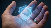 Digital security shield hologram floating above open palm with glowing particles for cybersecurity and data protection concepts in business technology.