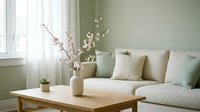 Modern minimalist living room interior with beige sofa, wooden coffee table, spring cherry blossoms in vase, natural light from window, cozy home decor.