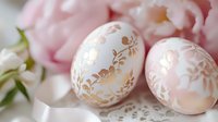 Decorated Easter eggs with gold leaf patterns and pink flowers in soft spring setting for holiday celebrations.