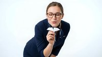 Young adult male with light skin tone and short brown hair wearing eyeglasses and dark navy blazer, holding blank white business card against white background for corporate branding and professional networking concepts.