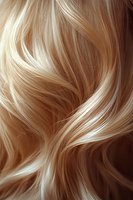 Flowing blonde hair strands with natural highlights and waves creating dynamic movement and texture, closeup macro shot showing detailed hair structure.