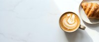 Overhead view of cappuccino with latte art beside croissant on marble surface, ideal for cafe, bakery, and breakfast-themed designs.