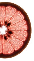 Fresh grapefruit half slice with vibrant pink flesh and detailed segment structure isolated on white background, suitable for food, nutrition, and culinary design projects.
